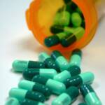 green capsules in front of an open pill container